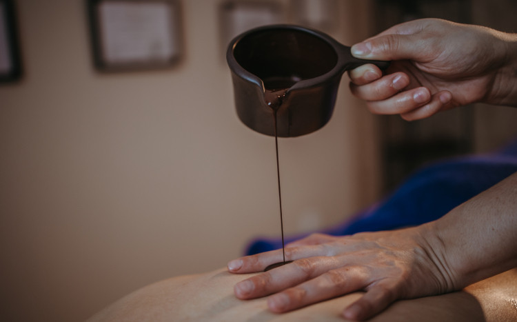masażystka wylewa czekoladę na plecy kobiety