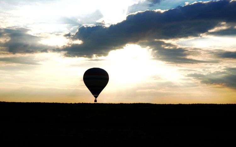Widok na lecący balon na tle wschodzącego słońca 