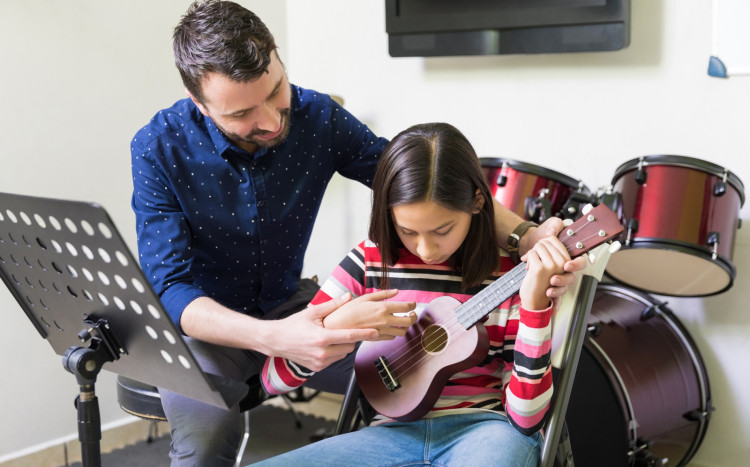 dziewczynka uczy się grać na ukulele z instruktorem