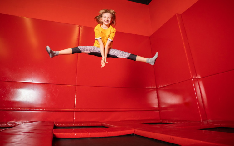 dziewczynka wykonuje szpagat podczas skakania na trampolinie