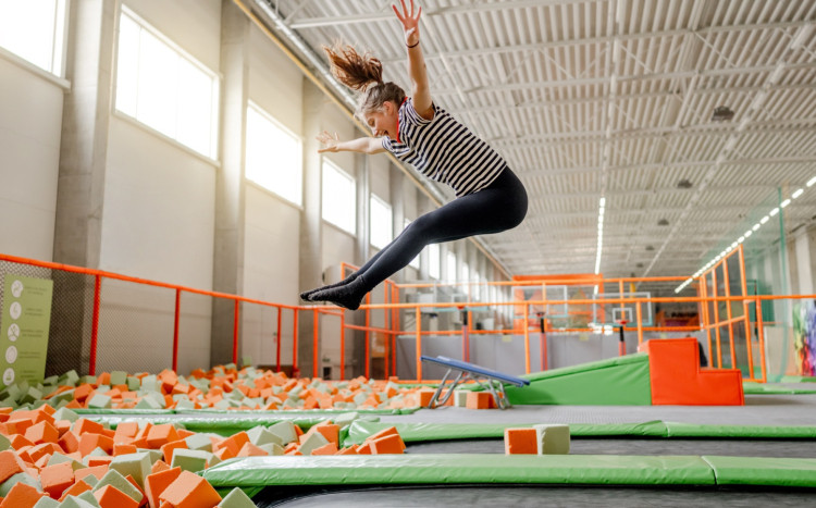 kobieta wskakuje do basenu wypełnionego kolorowymi gąbkami