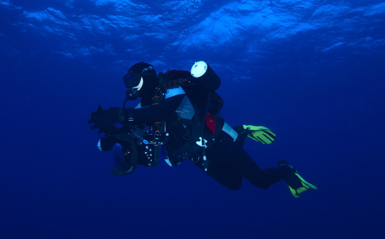 mężczyzna w skafandrze nurkuje po zmroku