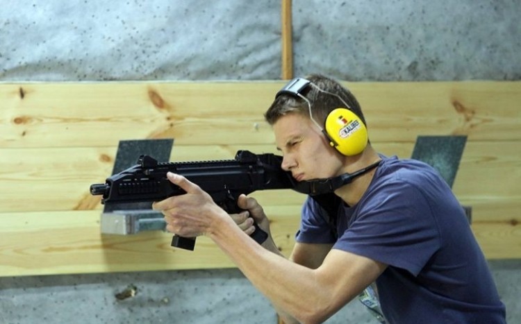 Chłopak w żółtych słuchawkach celuje z długiej broni