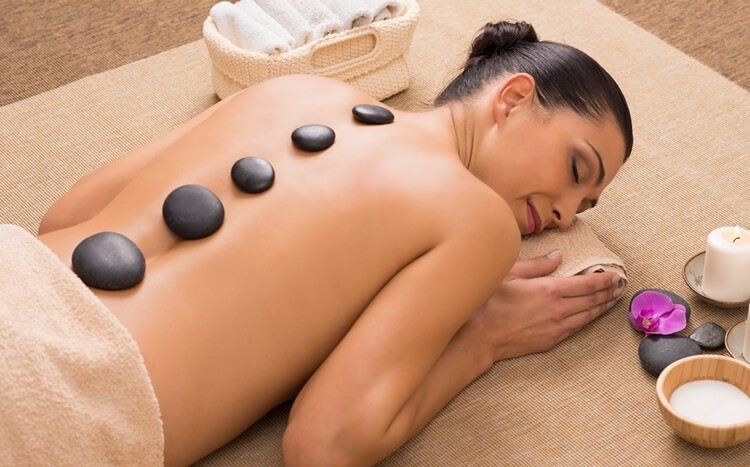 zrelaksowana kobieta podczas masażu gorącymi kamieniami