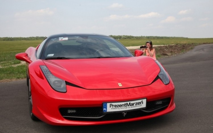 Kobieta fotografuje stojące Ferrari Italia