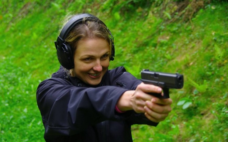 Uśmiechnięta kobieta z pistoletem w rękach