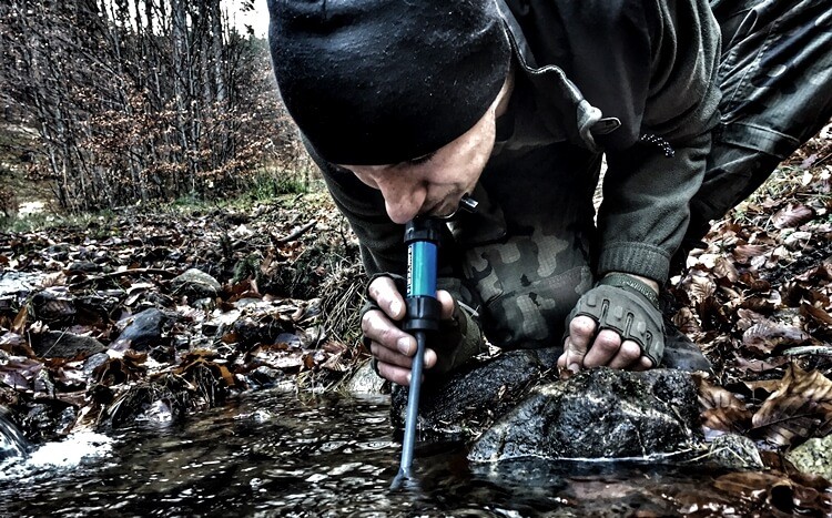 mężczyzna pije wodę przez specjalny filtr