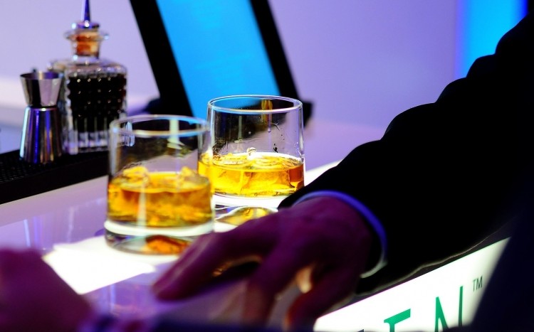 Dwie szklanki napełnione whisky stojące na blacie baru