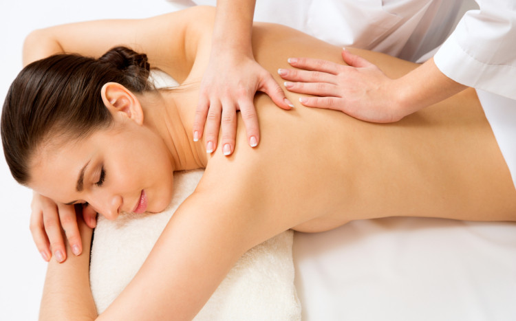 Dłonie masażystki na plecach zrelaksowanej kobiety podczas masażu