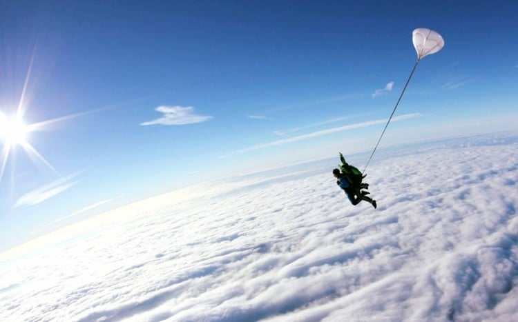 Mężczyzna z instruktorem lecący ponad chmurami, na tle błękitnego nieba
