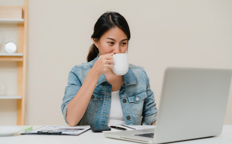 kobieta pijąca kawę przed komputerem