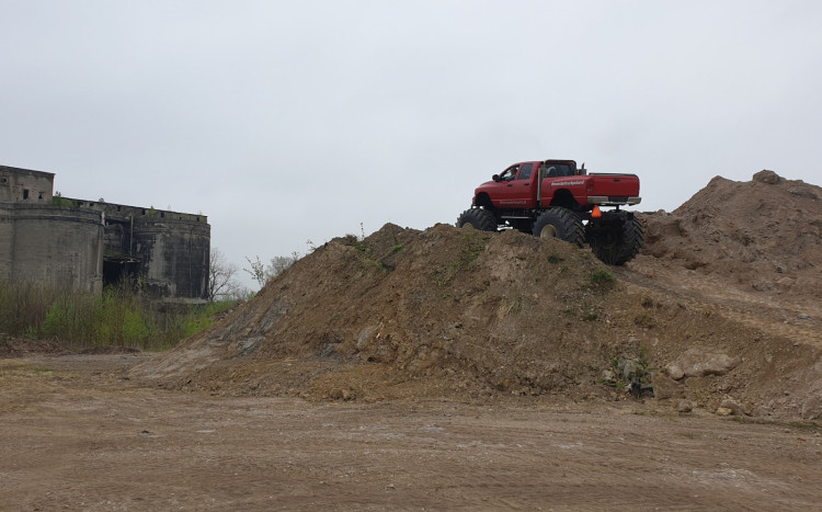 Czerwony Monster Truck wjeżdżający na wielką górę z ziemi