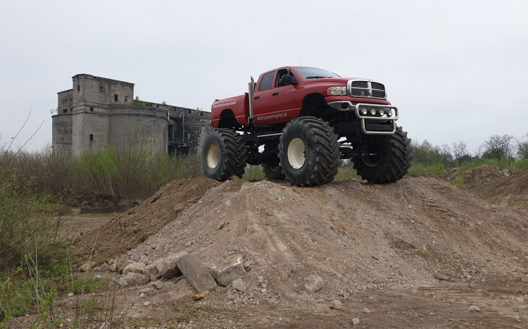 Duży i czerwony Monster Truck stojący na górce z ziemi