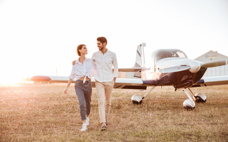 mały samolot i zakochana para na trawiastym lądowisku