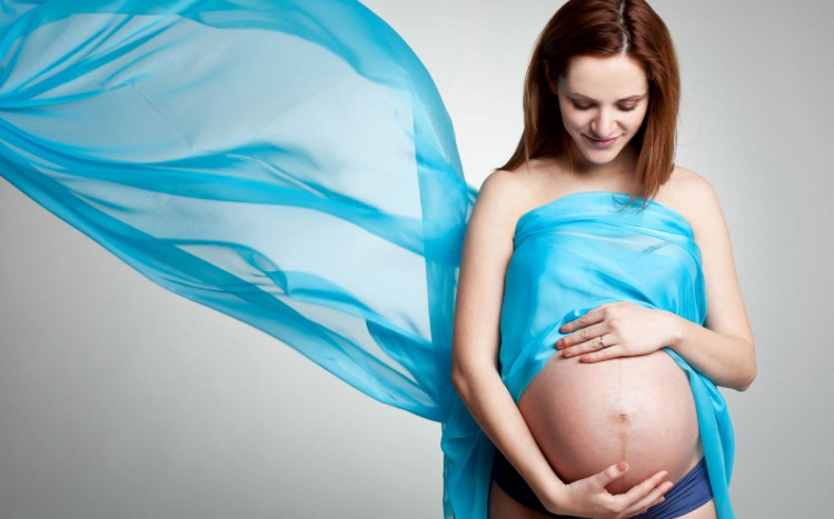kobieta trzymająca się za brzuch - sesja ciążowa