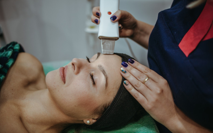 kosmetolog wykonuje peeling kawitacyjny na twarzy kobiety