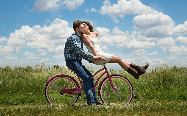 Para zakochanych na rowerze na łące.