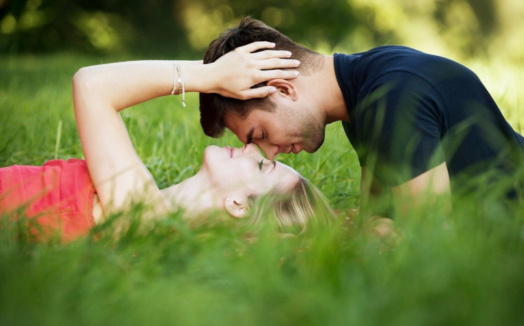 Zakochani w trawie twarzami do siebie.