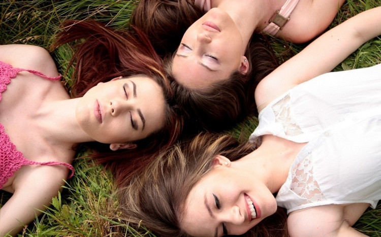 Trzy kobiety leżące na trawie.