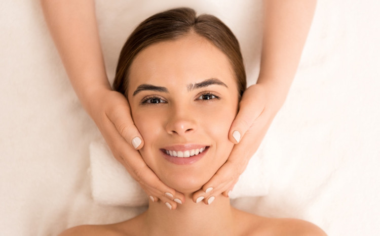 Uśmiechnięta kobieta na masażu twarzy.