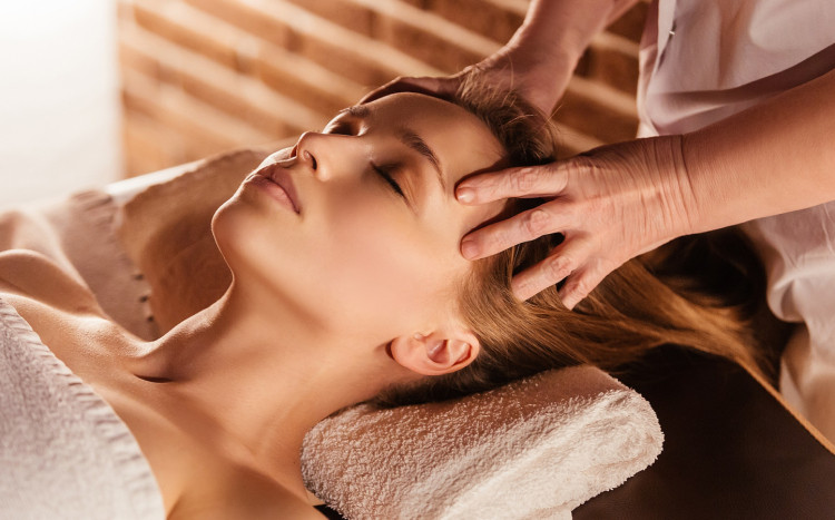 zrelaksowana kobieta podczas masażu głowy w spa