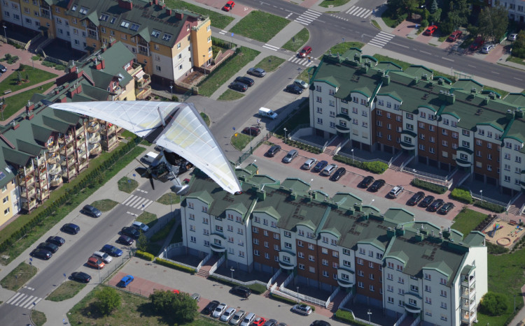 Widok z lotu ptaka na motolotnię lecącą nad osiedlami