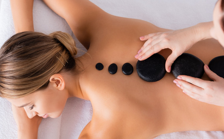 masażystka układa kamienie na plecach kobiety