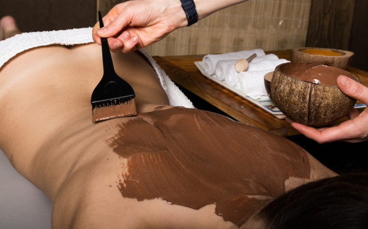 masażystka nakłada czekoladę na plecy podczas masażu