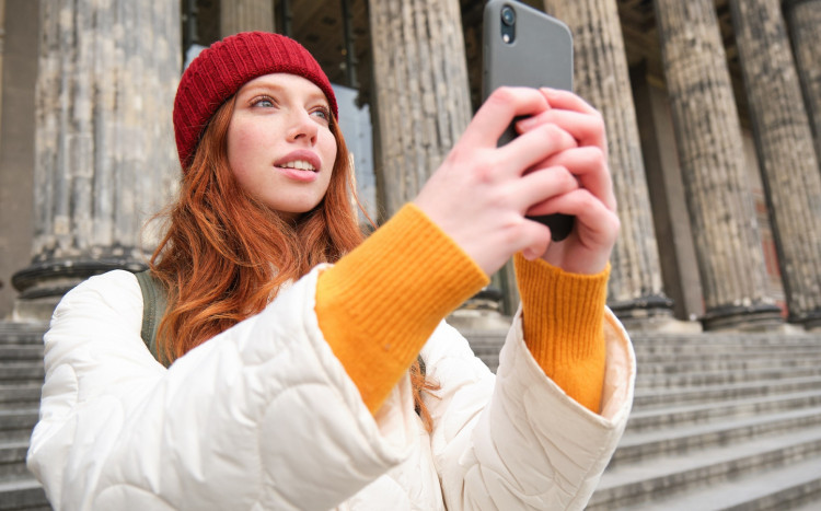 kobieta w rudych włosach trzyma smartfon w dłoniach