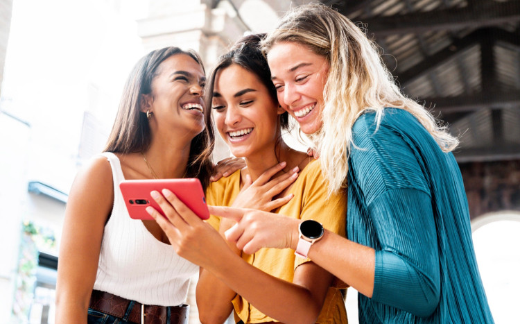 3 kobiety trzymają w ręku telefon i patrzą na ekran