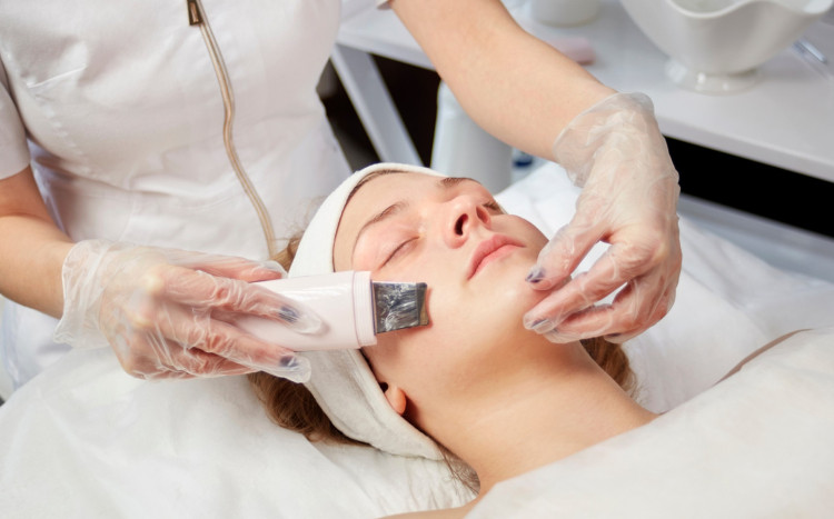 kosmetyczka oczyszcza twarz kobiety podczas peelingu kawitacyjnego