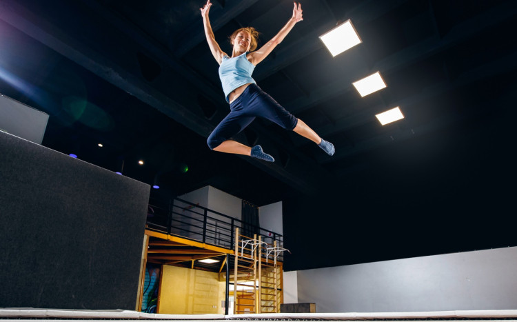 kobieta wykonuje akrobacje skacząc na trampolinie