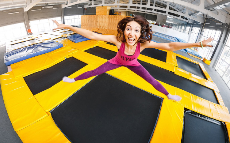 kobieta uśmiecha się do obiektywu skacząc na trampolinie