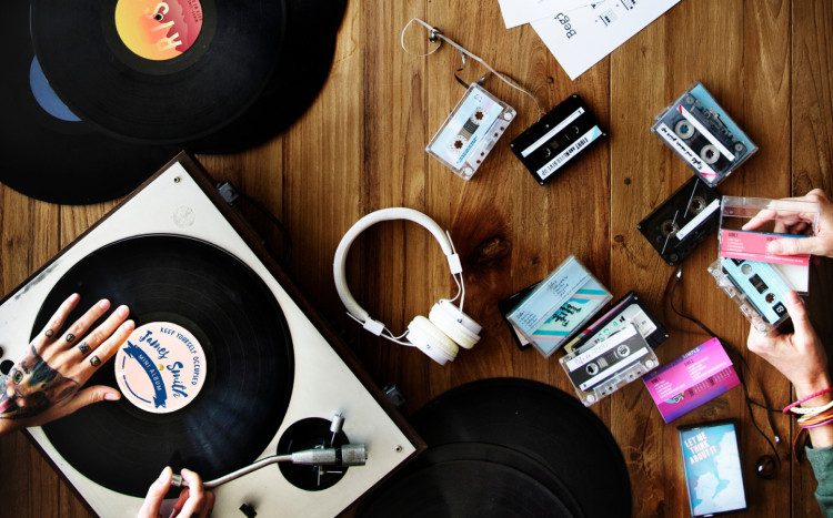 gramofon, płyty winylowe, słuchawki oraz kasety położone na podłodze