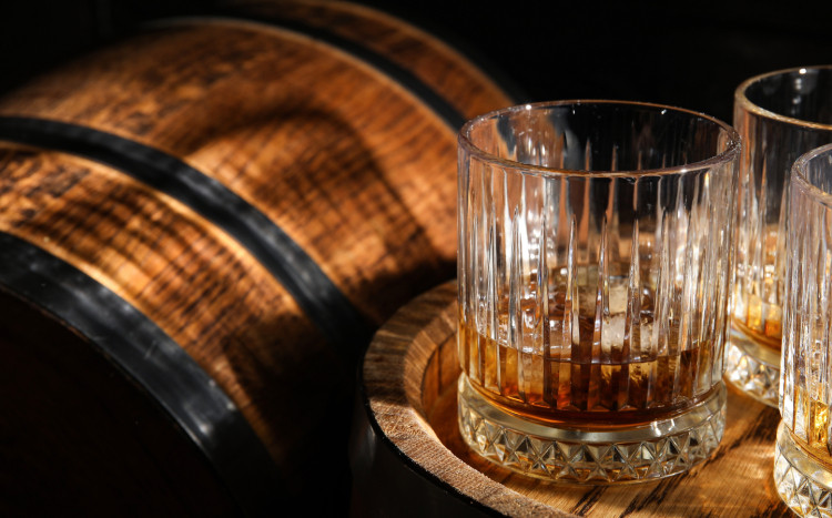 szklanki z whisky stojące na drewnianej beczce
