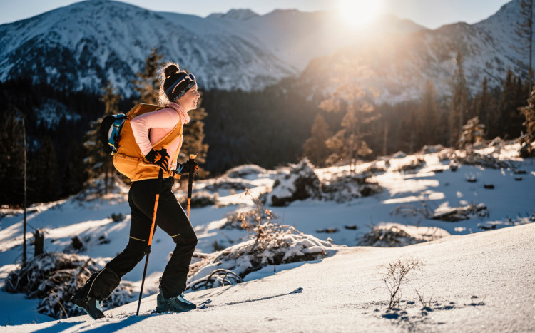 Kobieta podczas nordic walking w górach idąca po śniegu
