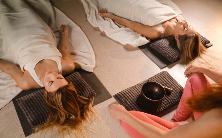 Dwie kobiety leżące na podłodze na plecach podczas masażu lub terapii dźwiękiem
