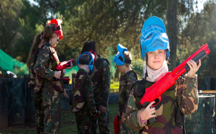 dziewczynka w niebieskim kasku podczas gry w paintball