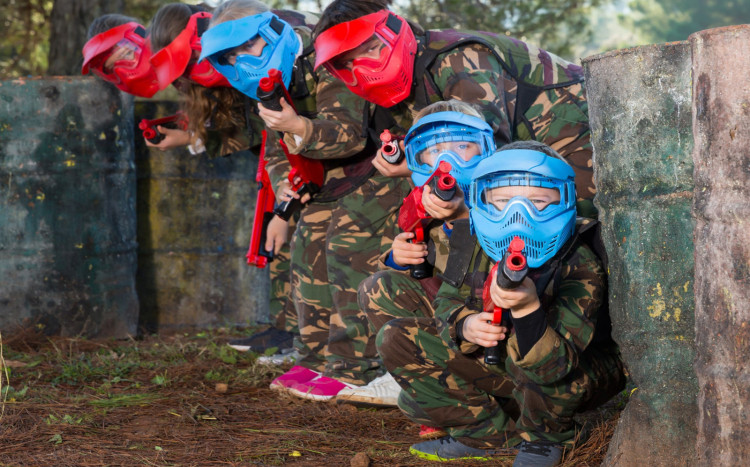 dzieci kucają podczas gry w paintball