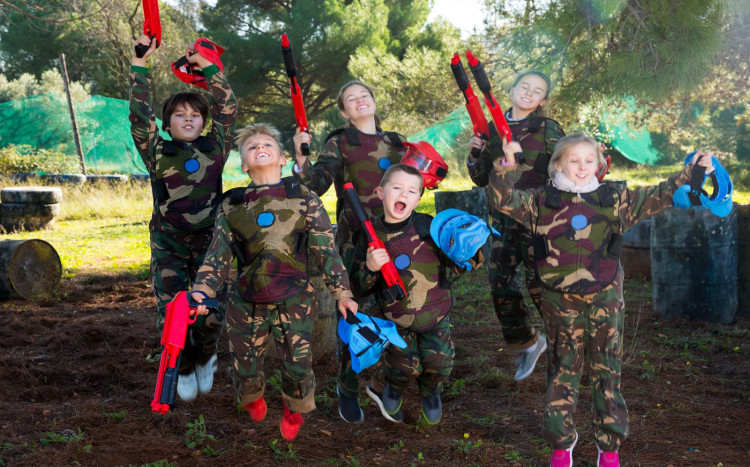 dzieci trzymają w górze karabiny do paintballa