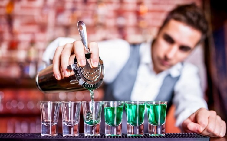 barman nalewa kolorowy alkohol do kieliszków