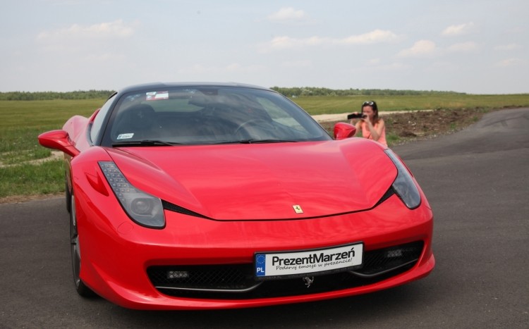 Ferrari Italia na parkingu, w tle widoczna kobieta robiąca zdjęcie