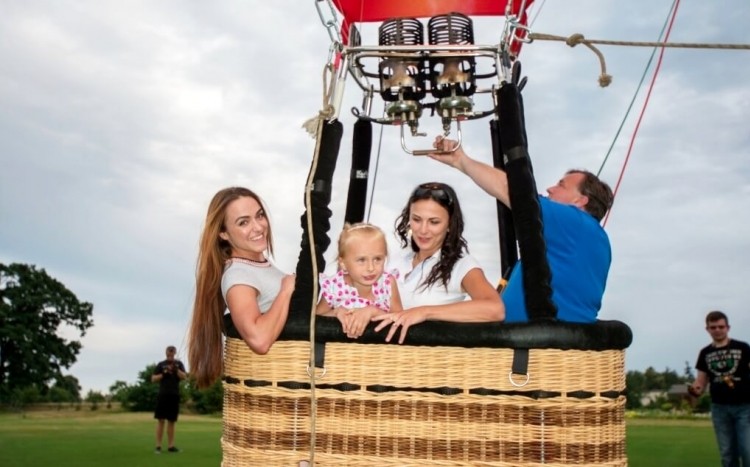 dwie młode kobiety z dzieckiem i pilot w gondoli balonu
